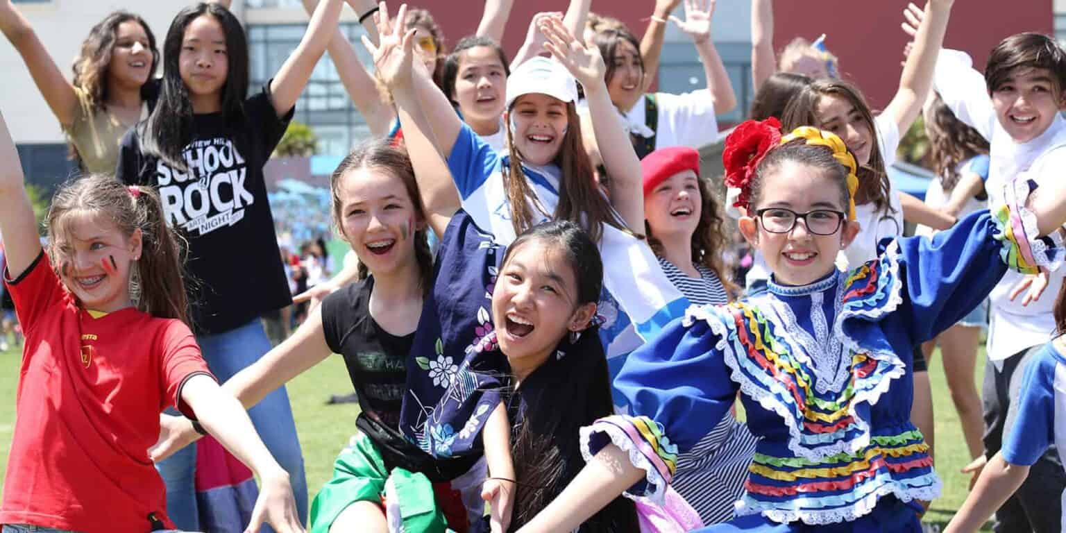 Vibrant group of diverse children celebrating outdoors at a school event, showcasing joy and multicultural unity.