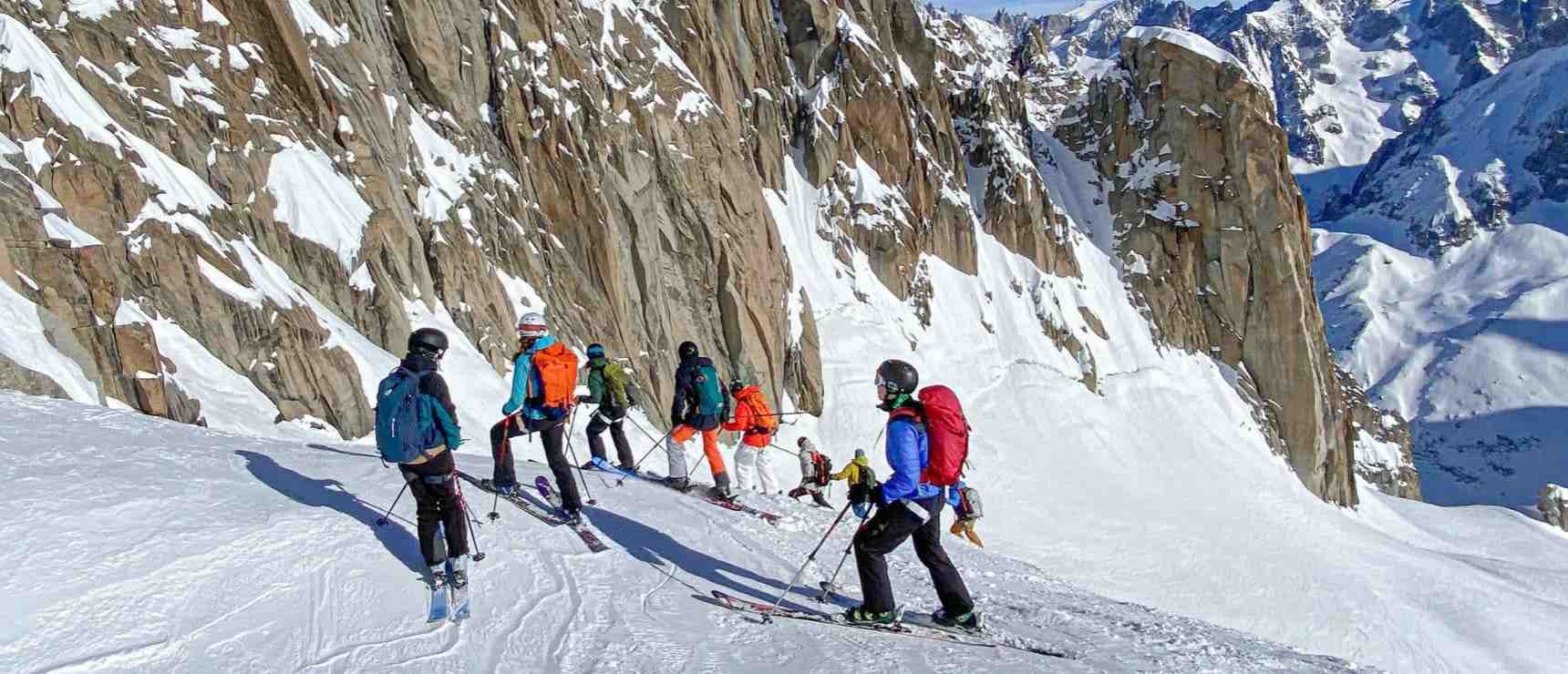 Alpine skiing team of students skiing on snow-covered mountain terrain for outdoor education and adventure.