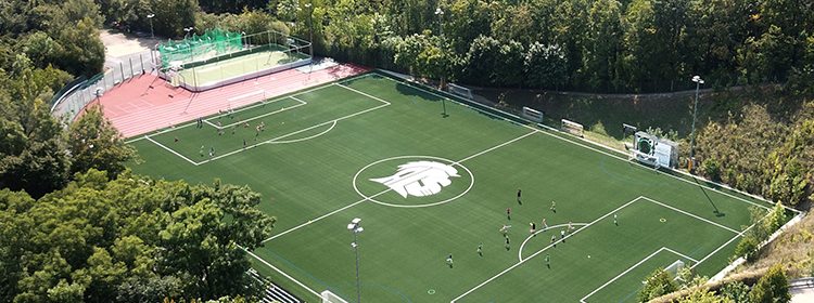 Modern sports complex with soccer field and tennis courts at prestigious World Schools campus.