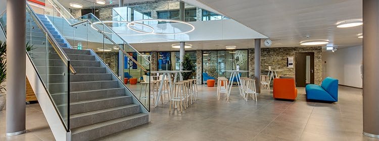 Modern school lobby with seating and staircase at World Schools campus, promoting a comfort-focused learning environment.