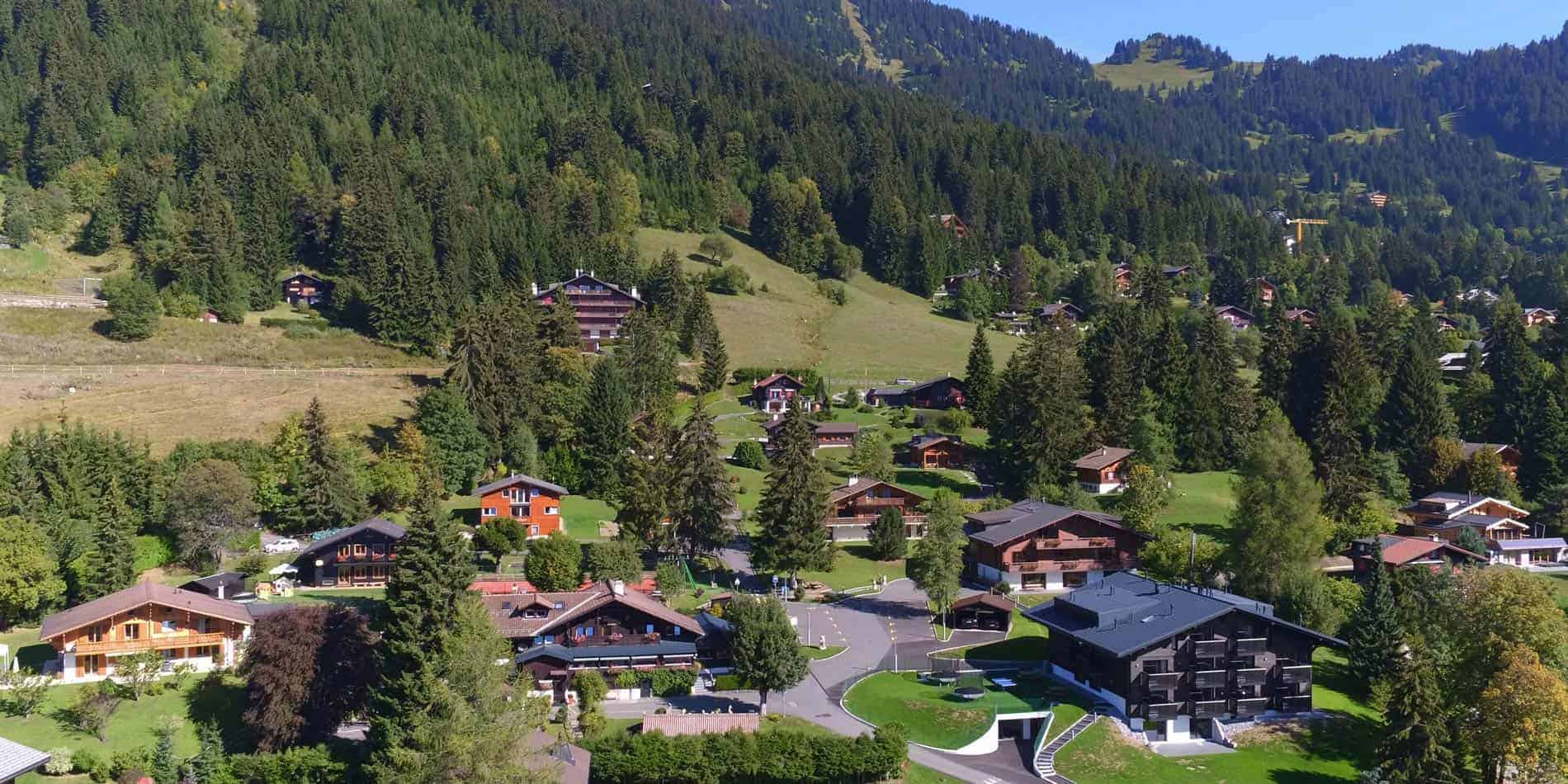 Okullar 4 Charming mountain village with alpine houses and lush greenery in a scenic landscape.