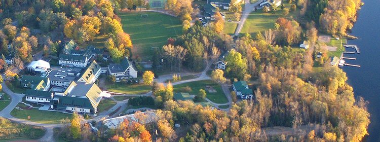 Modern world school campus surrounded by lush trees and water bodies in fall season.