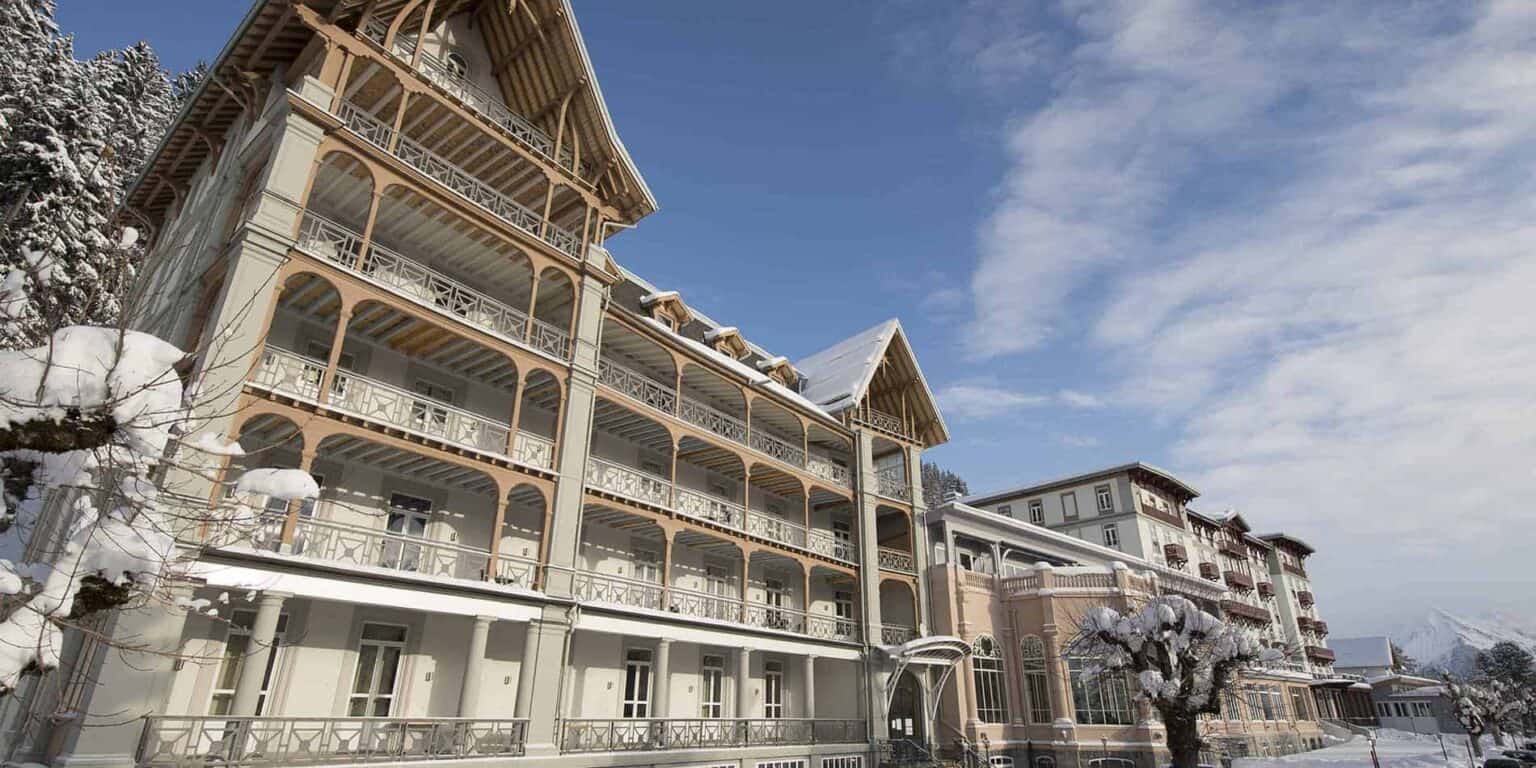 Elegante località montana innevata in Svizzera, con architettura classica e paesaggio invernale panoramico.