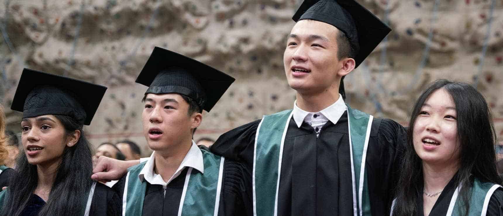 Graduates celebrating at a World Schools graduation ceremony in academic regalia.