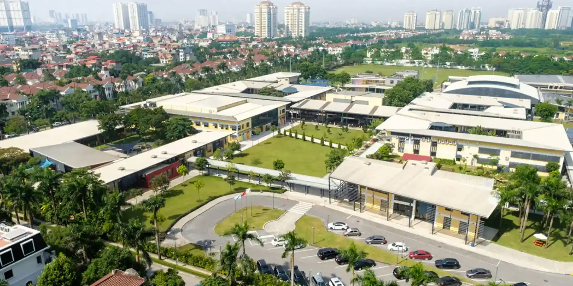 المدارس 4 Modern World Schools campus with lush greenery and city skyline backdrop.