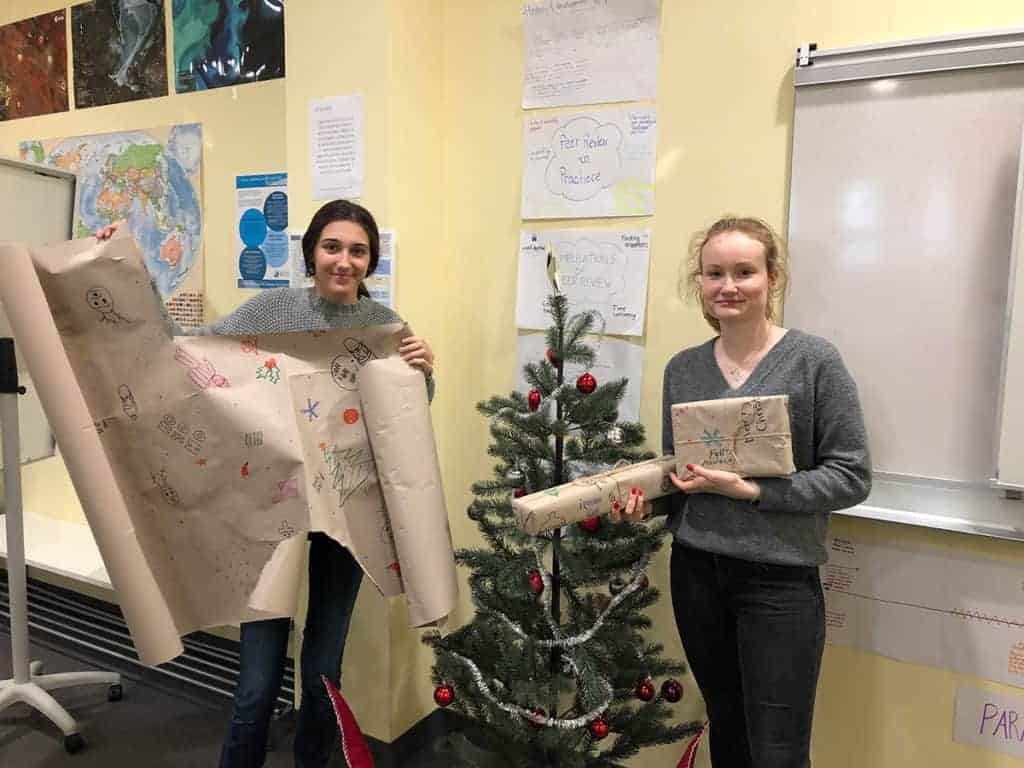 Duurzame cadeauverpakking voor de feestdagen 2 Student opening holiday gifts from school during Christmas time at a classroom celebration.