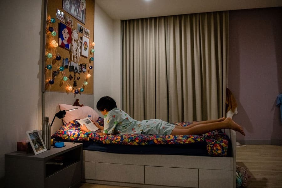 寄宿的学业优势 2 Comfortable student reading in a cozy, well-decorated bedroom at an international school.