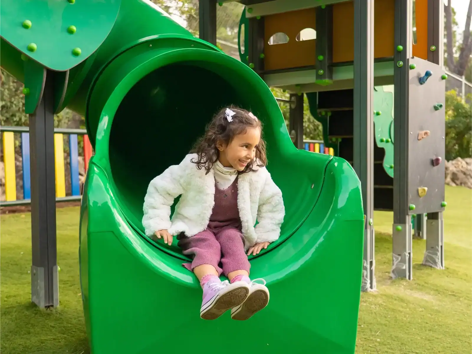 Child playing on a green slide at Liceo Europeo playground.
