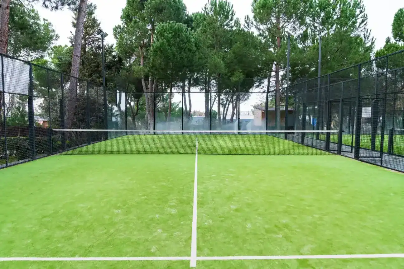 Tennis court at Liceo Europeo with well-maintained artificial grass and surrounding fencing.