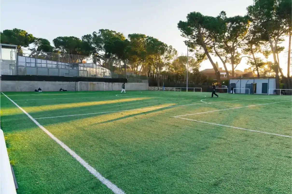 Soccer field at Liceo Europeo with well-maintained grass and surrounding trees.