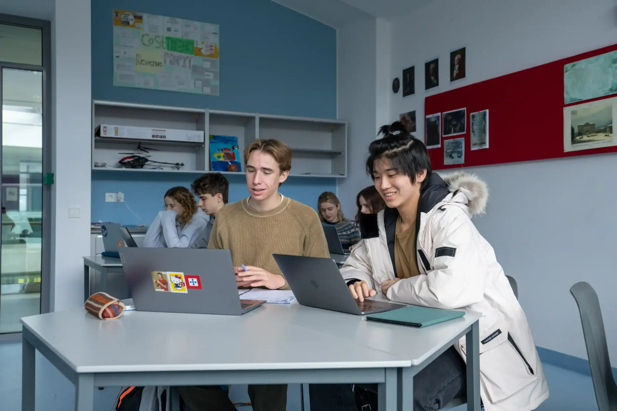 Modern international student classroom at a prestigious world school with engaged students working on laptops.