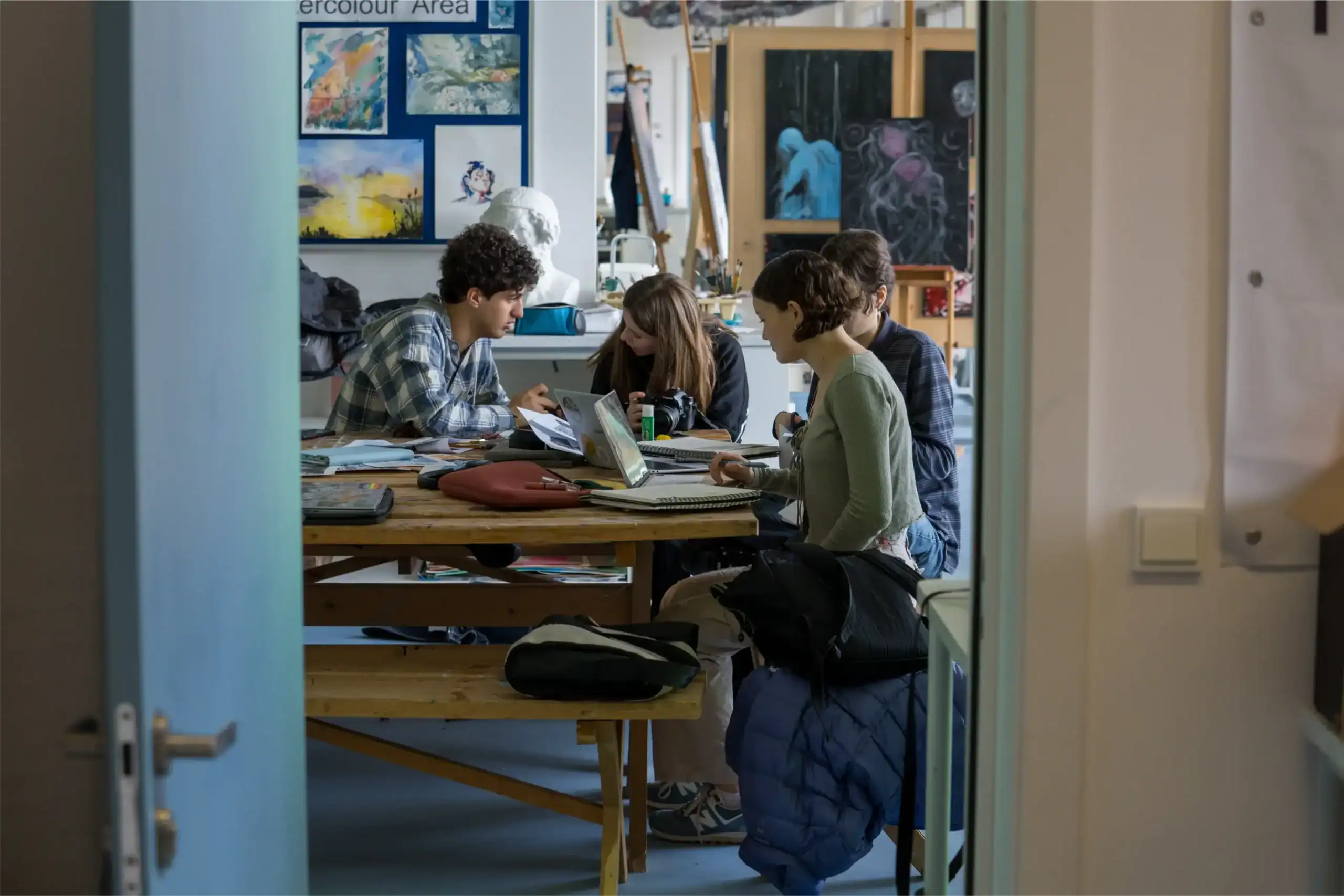 Creative students collaborating at art school studio, engaging in visual arts education, learning, and artistic development.