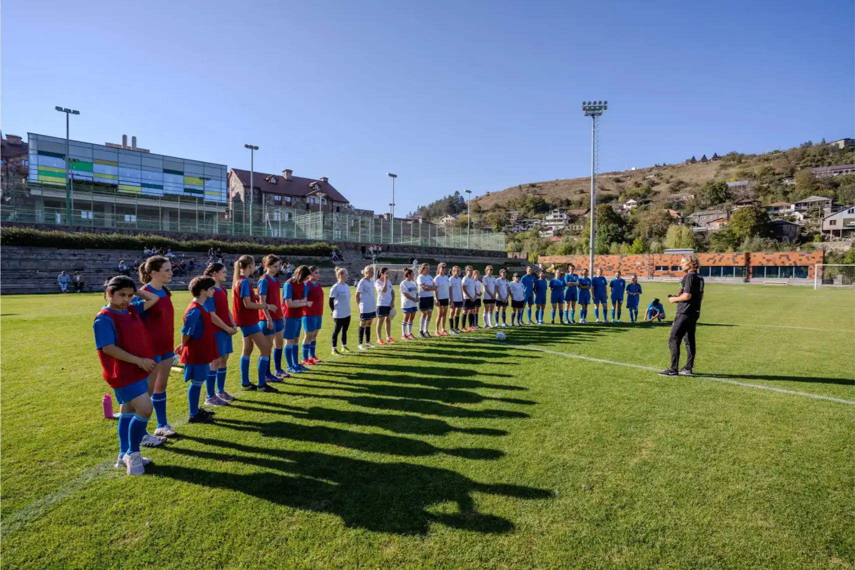 Young female and male students participating in a rugby practice on a university sports field.