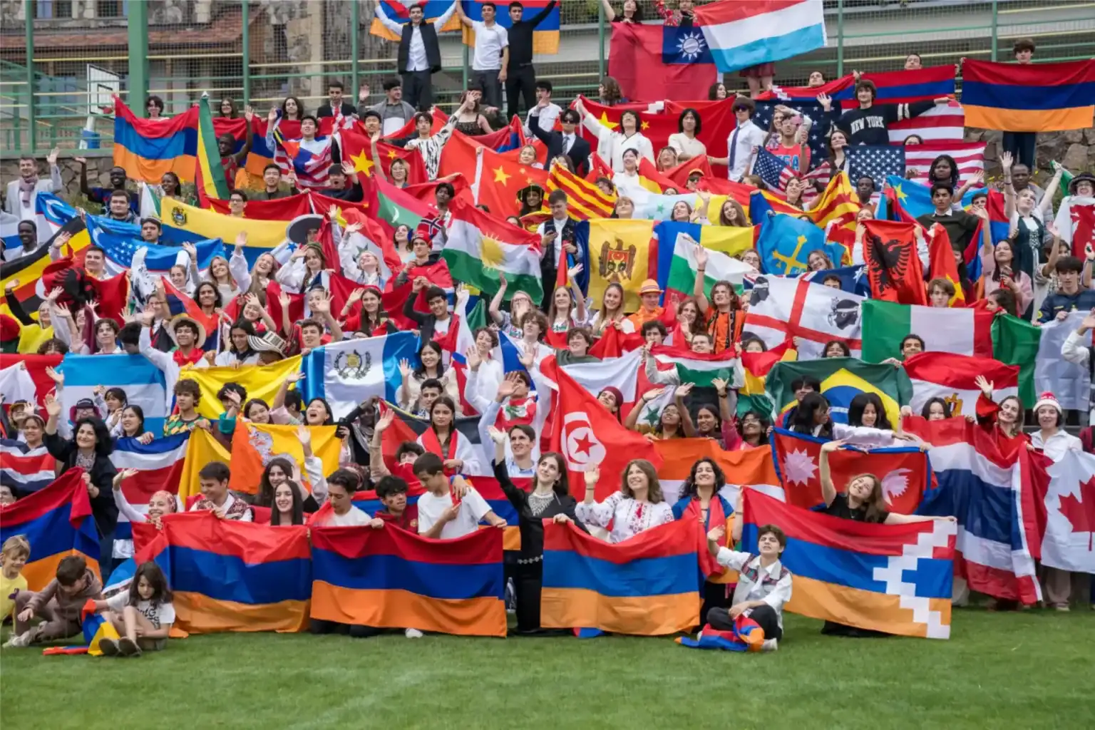 Diverse students holding international flags at a global school event, promoting multicultural education and diversity.