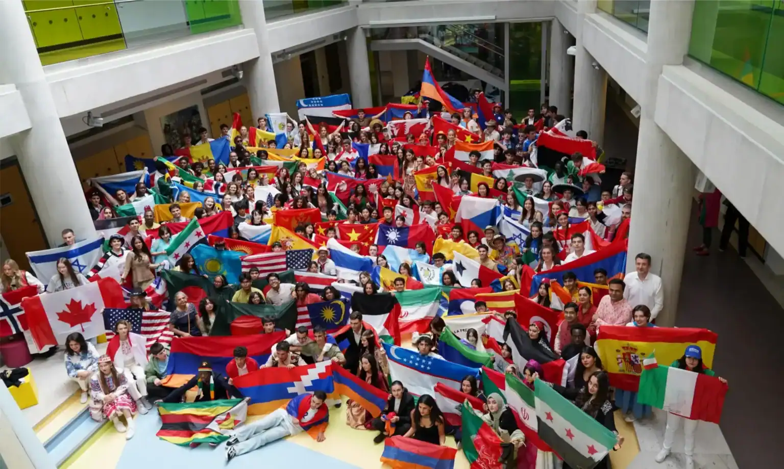 Diverse students holding international flags at a global school event in a modern educational setting.