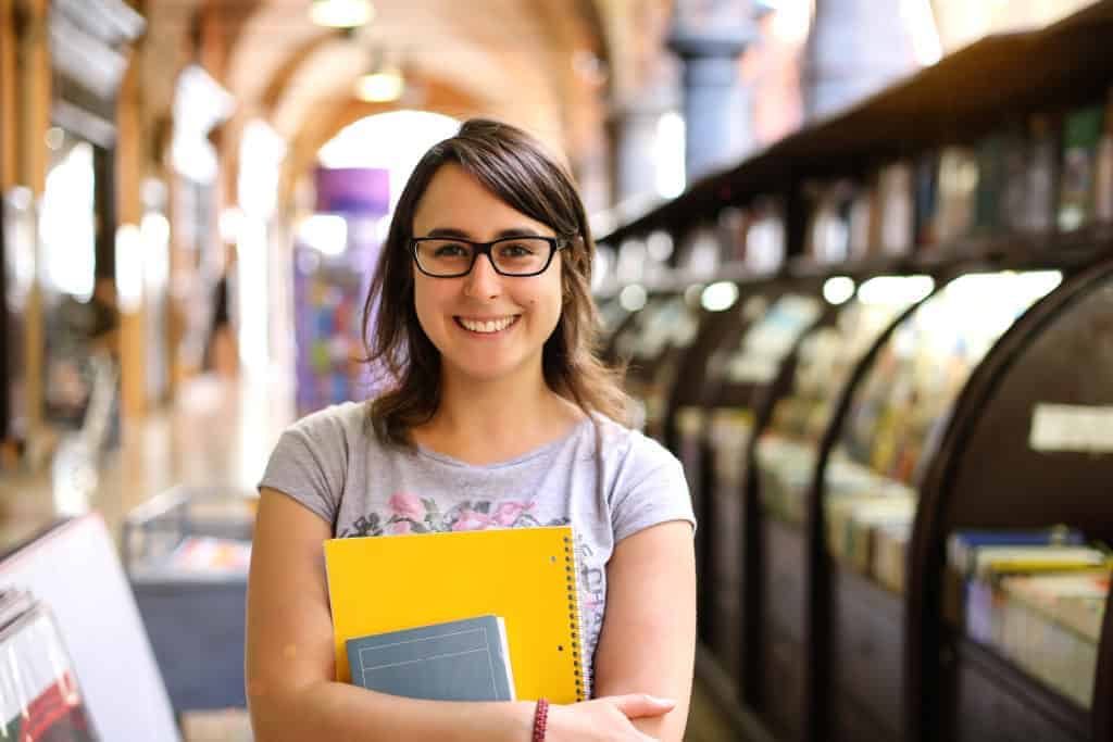 Przygotowanie dziecka do udanej rozmowy kwalifikacyjnej w szkole 2 Bright smiling student holding books at a school library, focused on international education and global school options.