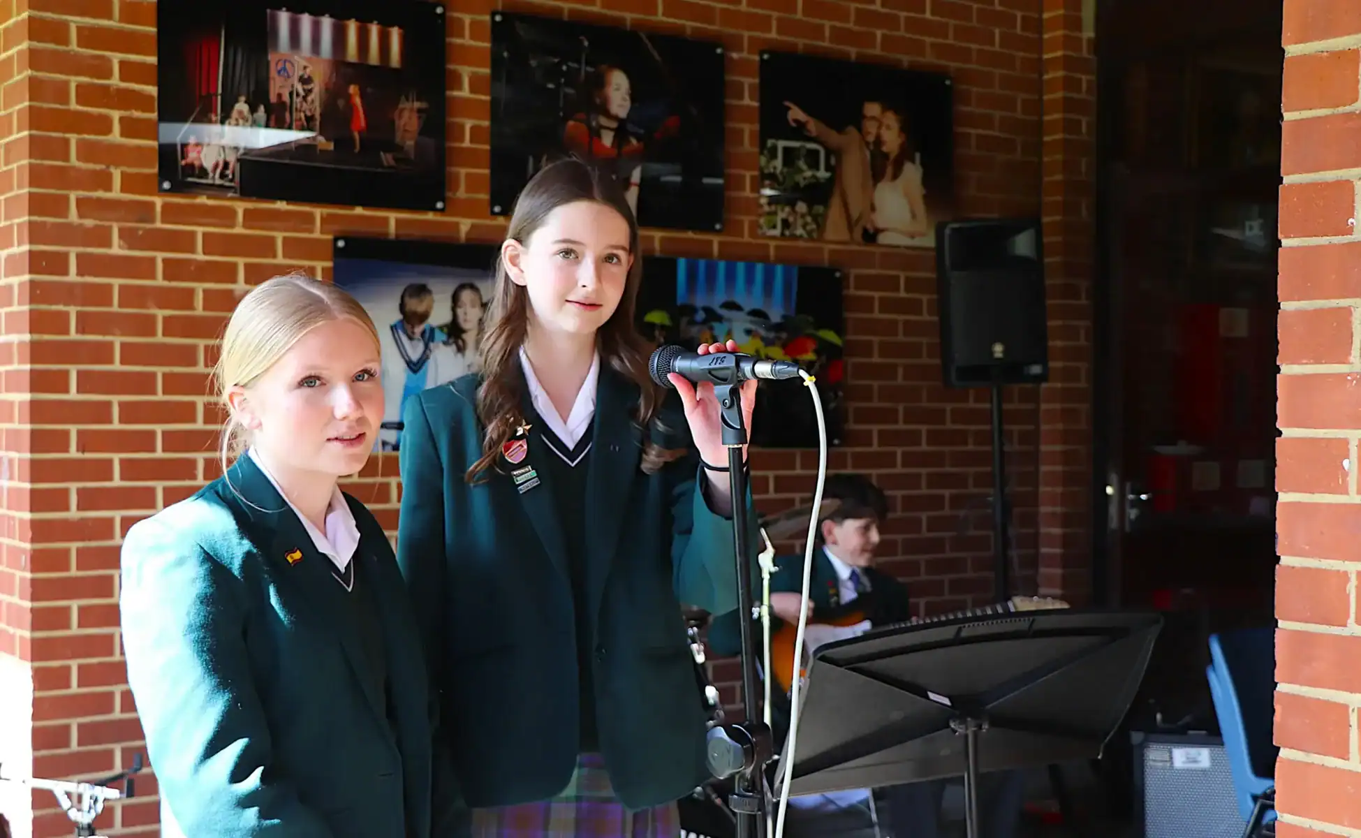 Students performing at a school event in a brick-walled hall.