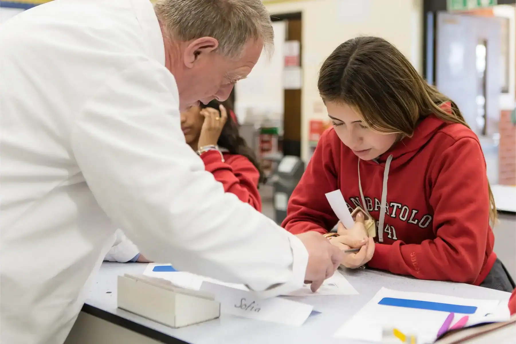 Student receiving hands-on science instruction from teacher in classroom.