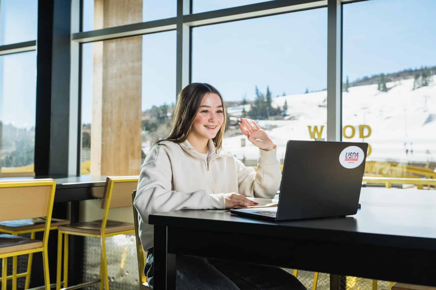 Young woman participating in online learning at a modern school with large windows.