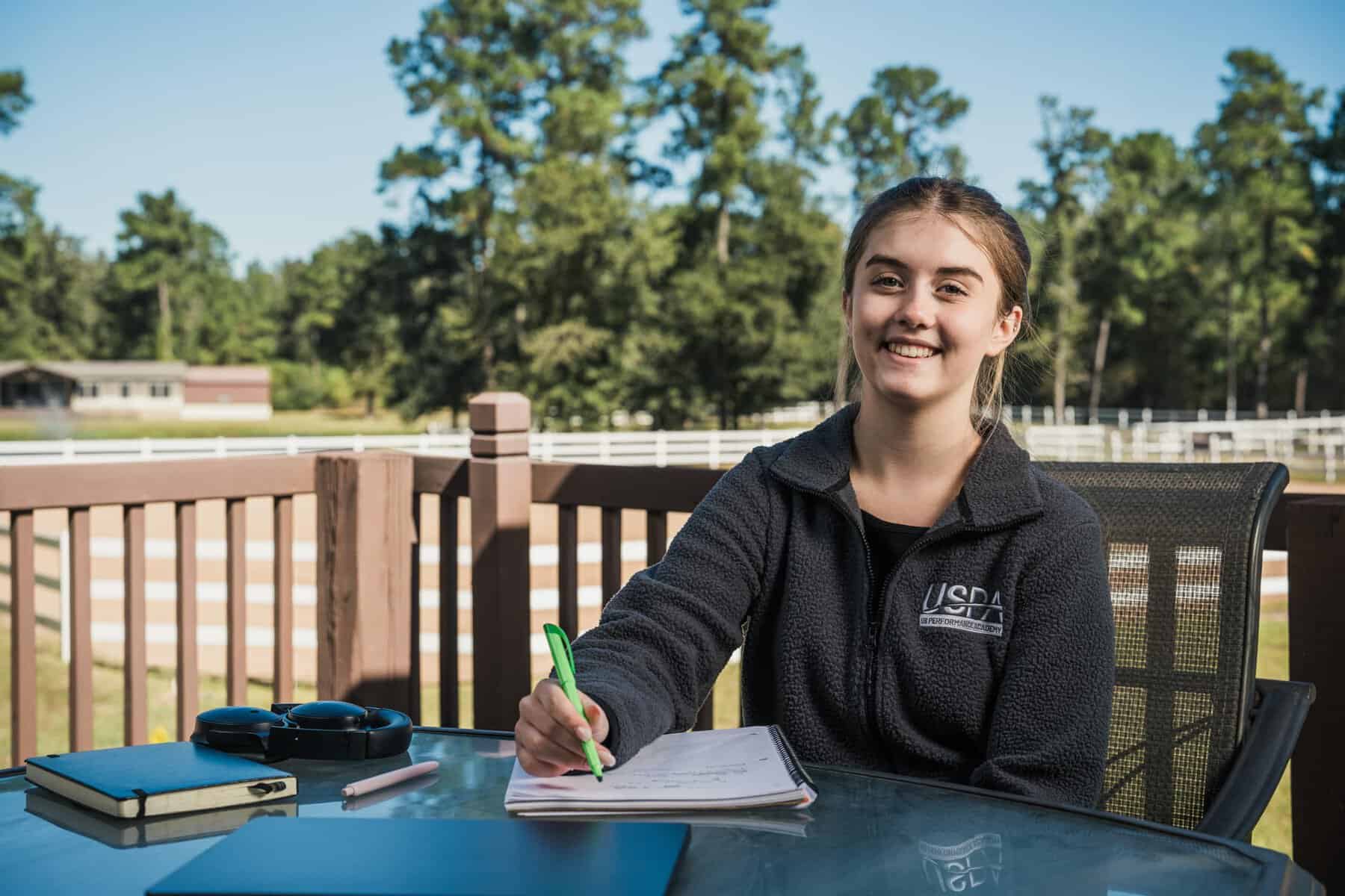 Smiling girl studying outdoors at USPA online school.