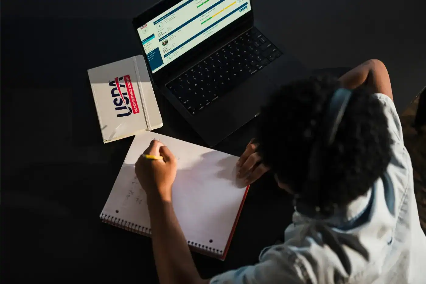 Student studying online at a private middle and high school with a laptop and notebook.