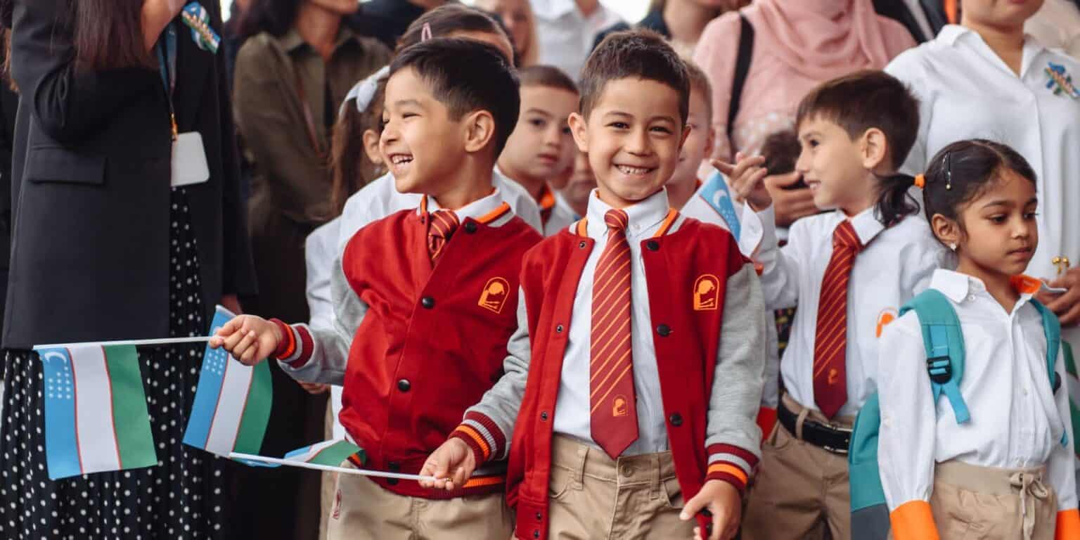Escolares felices en uniforme participando en un evento escolar al aire libre, diversos estudiantes sonriendo, ambiente de aprendizaje, celebración de las Escuelas del Mundo.