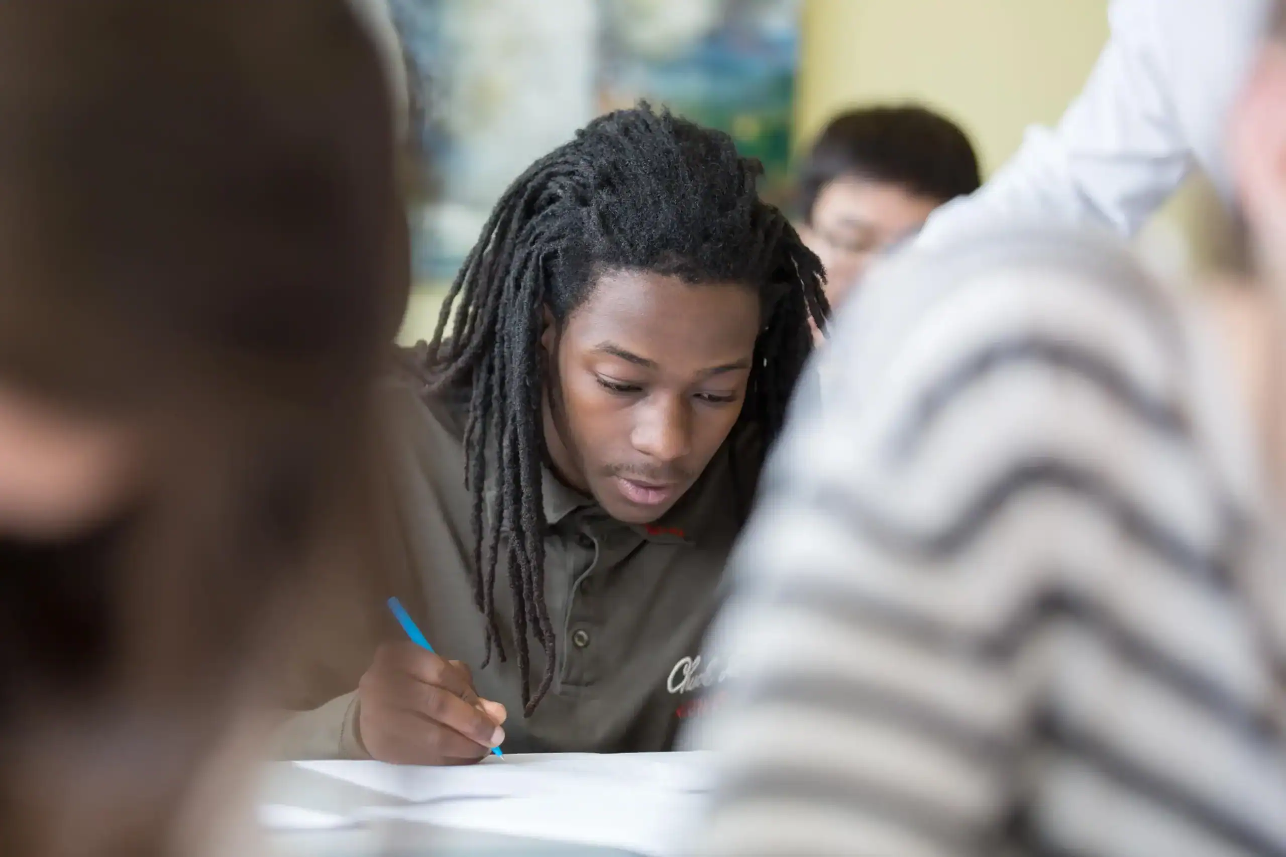 Diverse student studying and taking notes in a multicultural classroom environment.