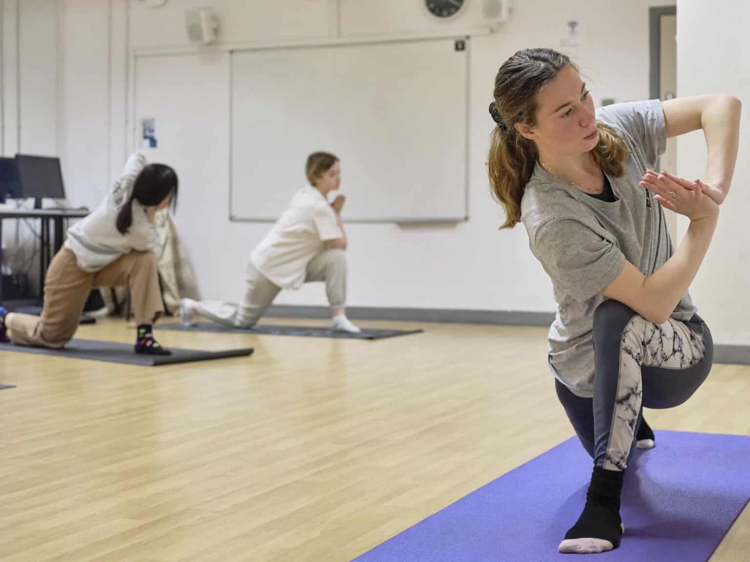 Yoga class with students and instructor in a school setting, promoting wellness and mindfulness.