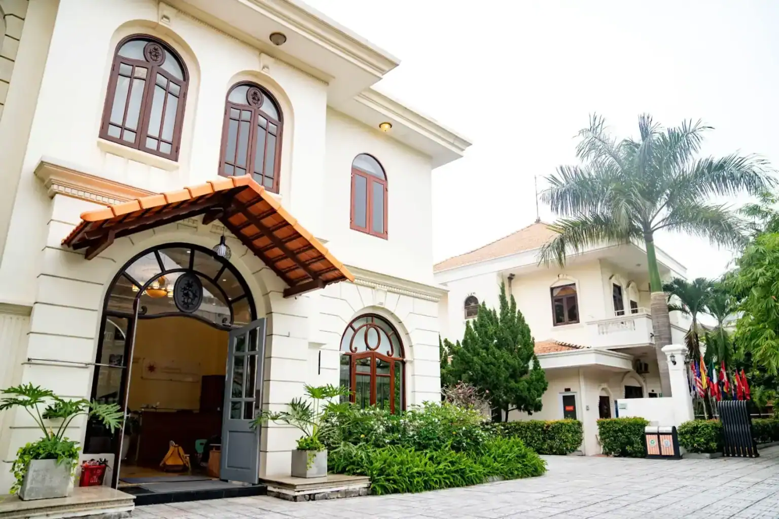 Warmly lit luxurious international school building with lush greenery and flags, offering top-quality education.