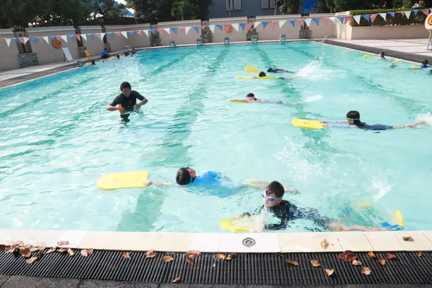 Children learning swimming skills at a school pool, engaging in water safety and aquatic activities.