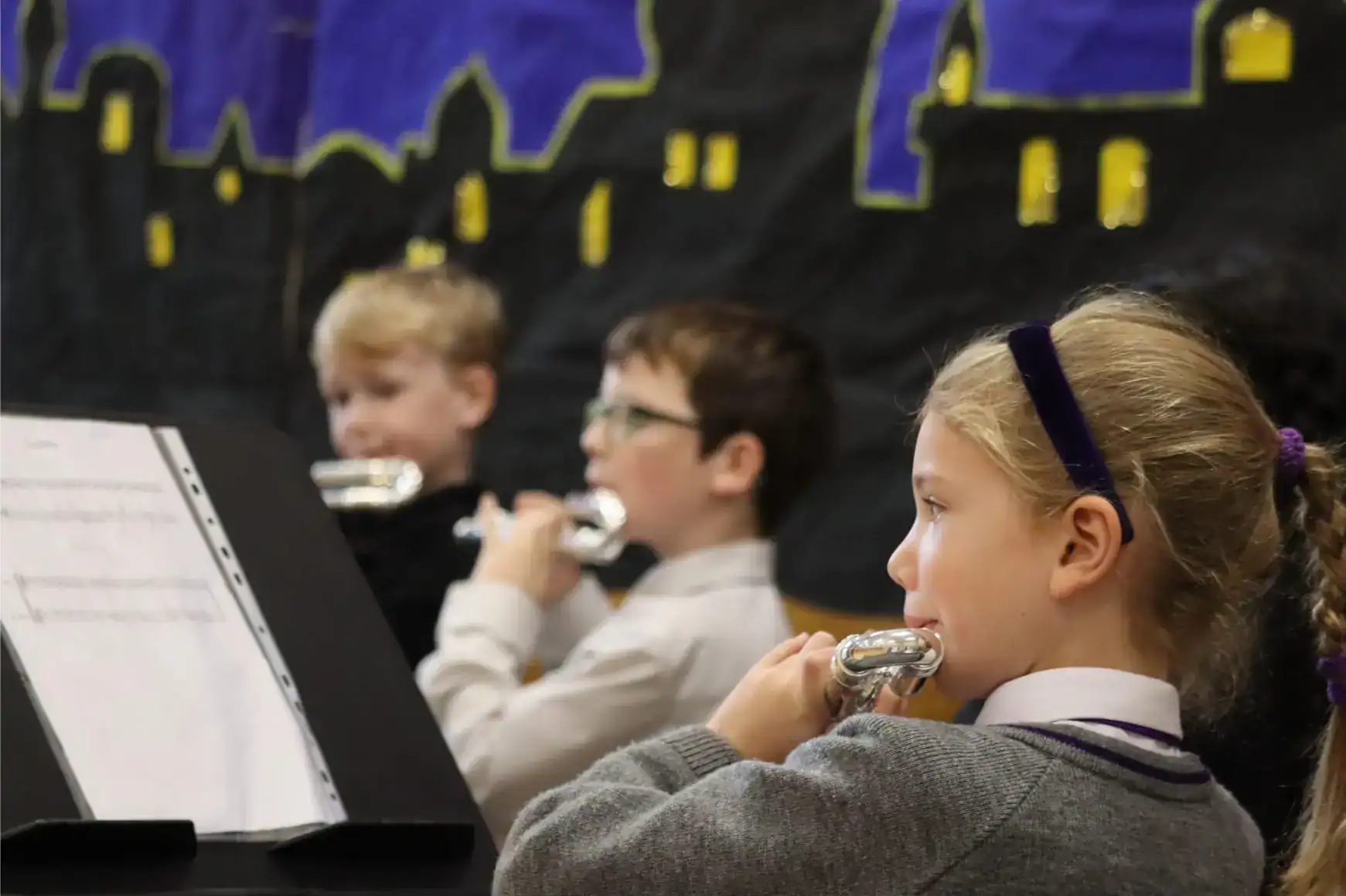 Focused children playing flutes during school music class at an international school event.