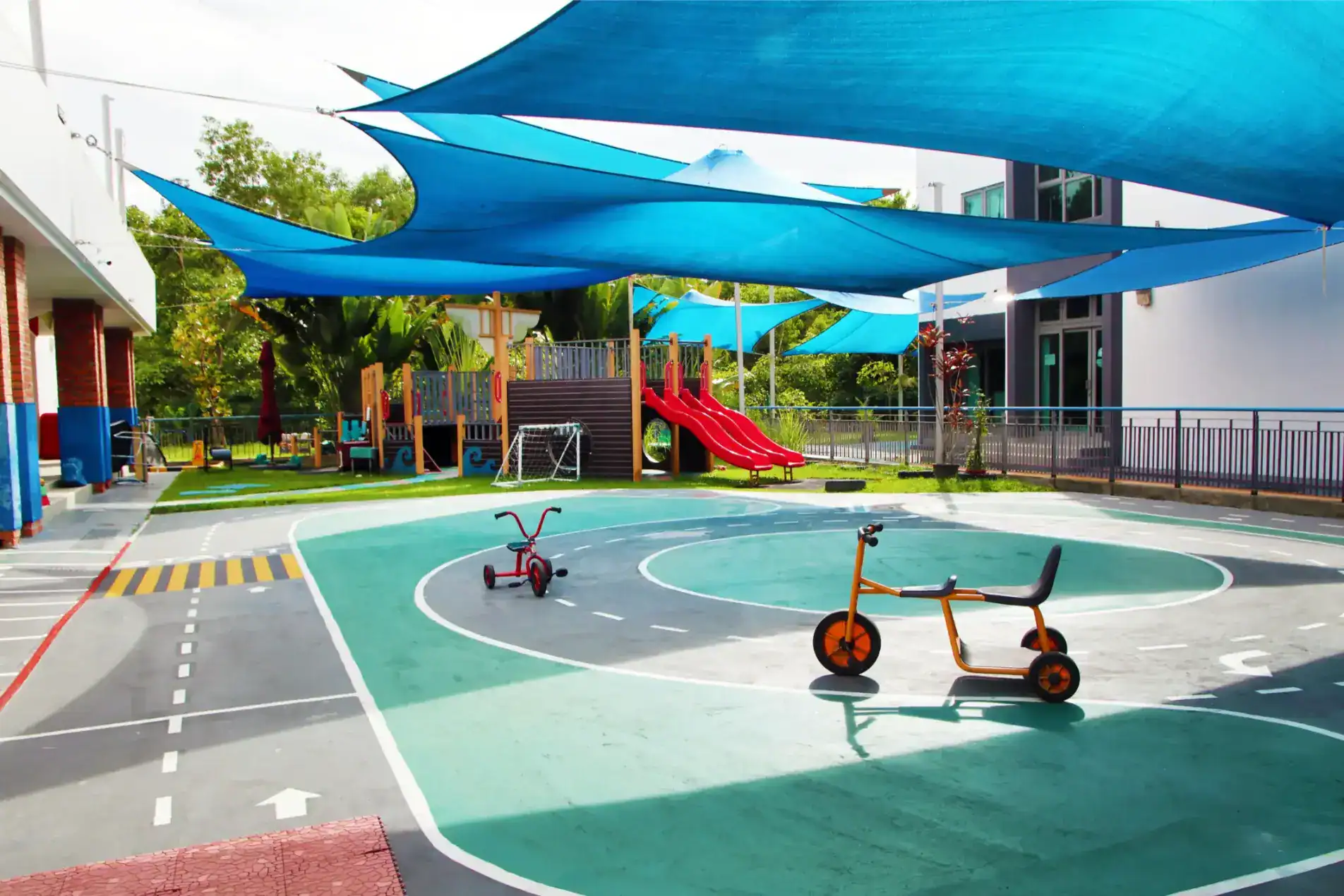 Bright outdoor playground with shade sails, bikes, and slides, ideal for children at leading international schools.