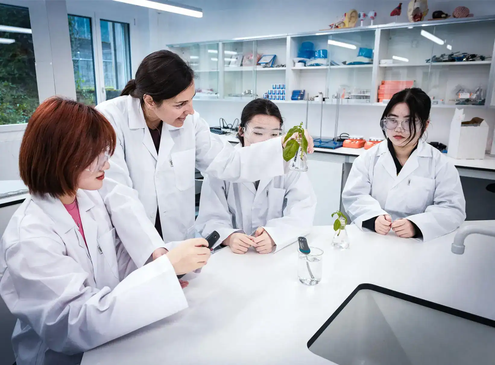 Highly diverse group of students in lab coats conducting a science experiment at a modern international school.
