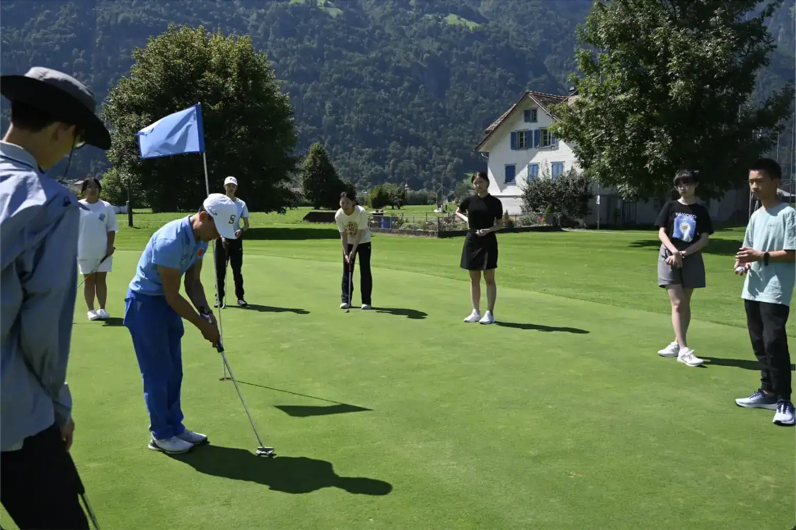 Students practicing golf outdoors at a scenic school campus in Switzerland.