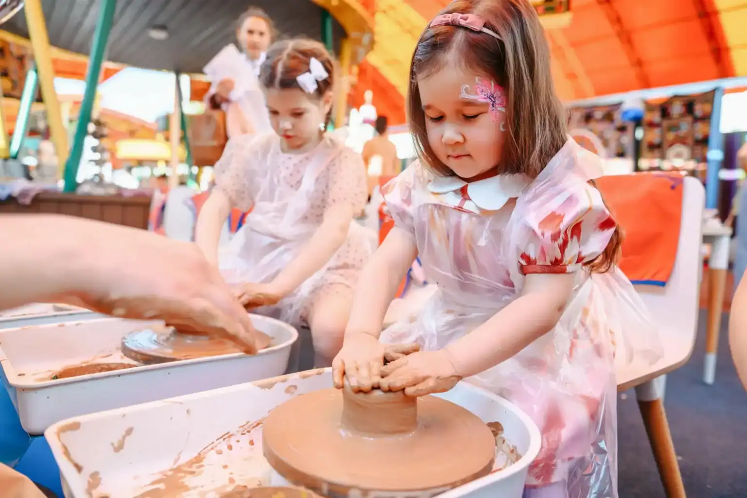 Niños participando en una clase de alfarería en un acto escolar, fomentando la creatividad y el aprendizaje práctico.