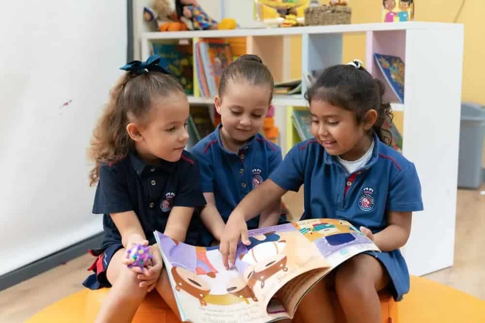 Bright preschool children reading a colorful storybook together in a vibrant classroom setting.