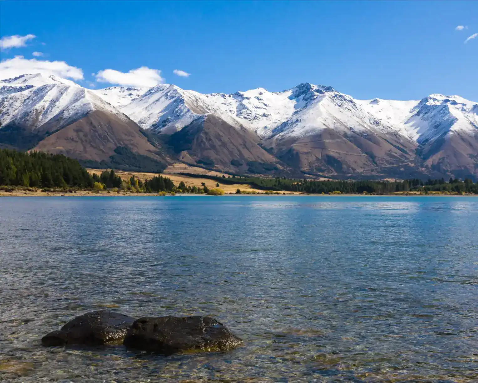 Snow-capped mountains and crystal-clear lake in New Zealand. Nature, adventure, scenic views, outdoor exploration.