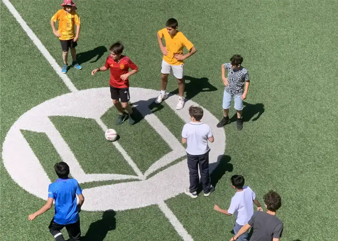 Children playing soccer on a green field at a world school sports event.