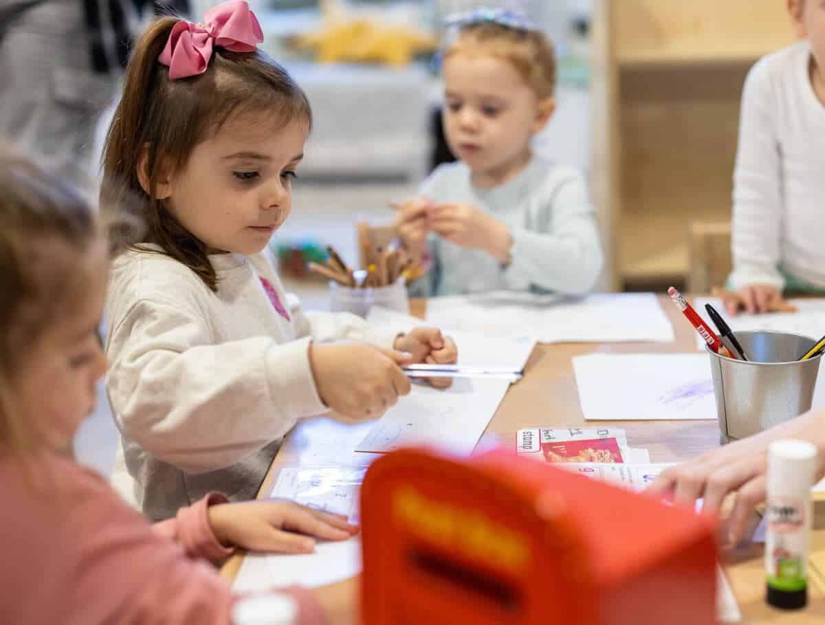 Young children engaged in art activities at a classroom table for early childhood education.