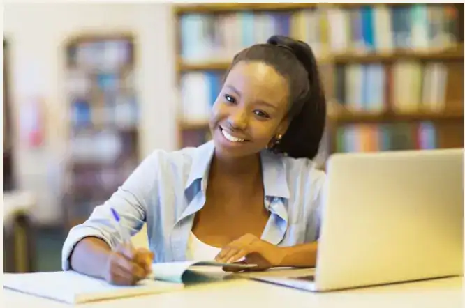 Bright smiling student studying at library with laptop, promoting global education via World Schools.