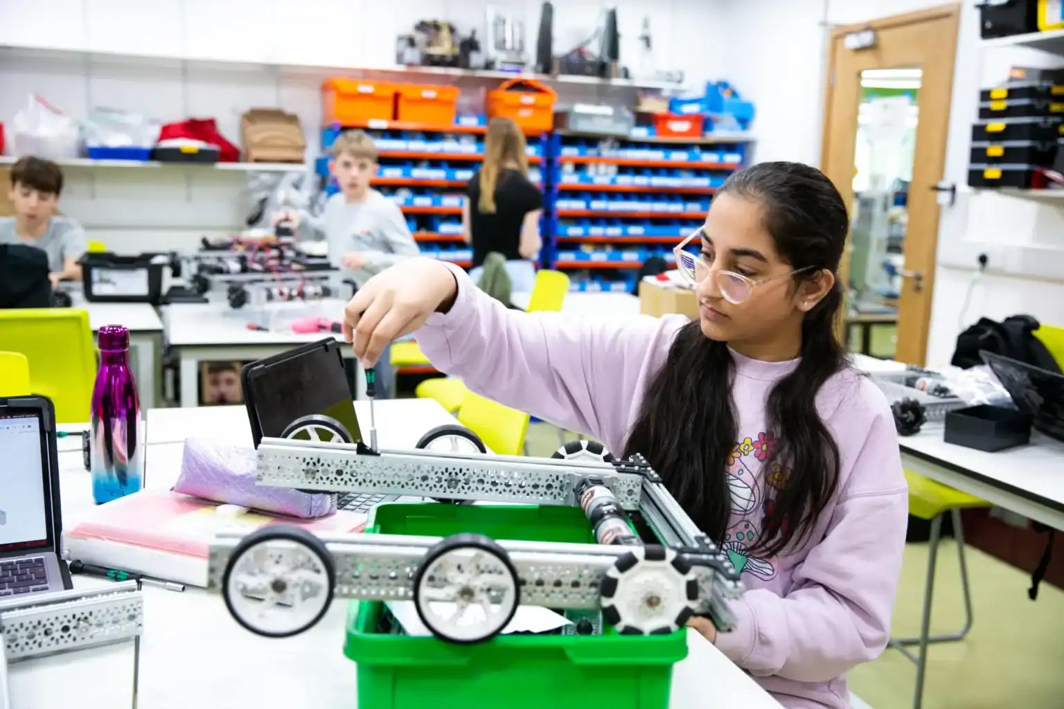 Young girl assembling a robotics project in a school STEM classroom.