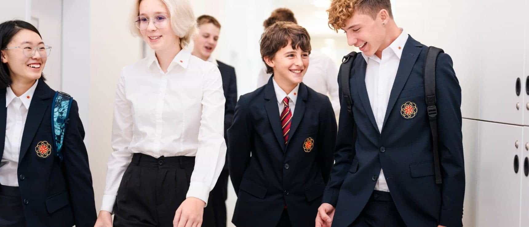 Bright diverse students in school uniforms walking in hallways at international school.