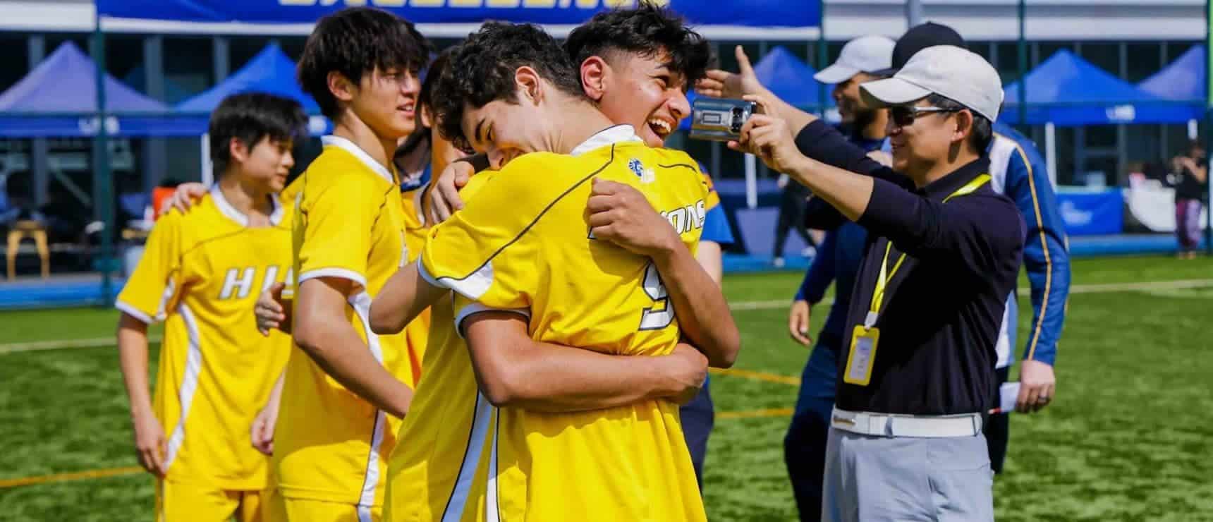 Youth soccer team celebrating victory after match at outdoor stadium.