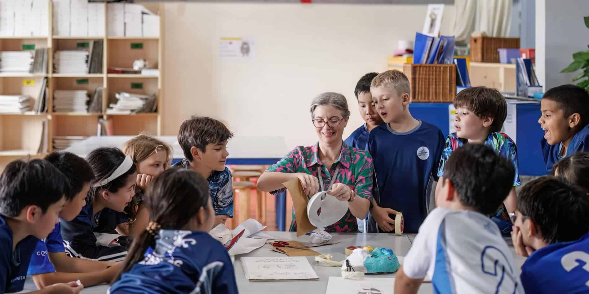 Children's classroom activity with teacher, STEM project, and creative art materials, fostering learning and teamwork.