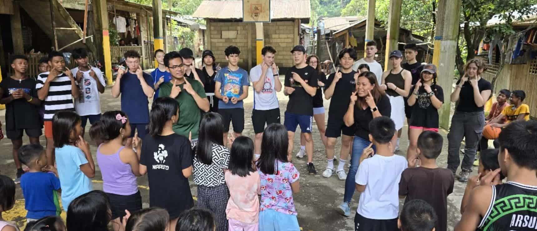 Girls and boys participating in outdoor school activity at a village school, group learning, young students, outdoor classroom, community education, inclusive environment.