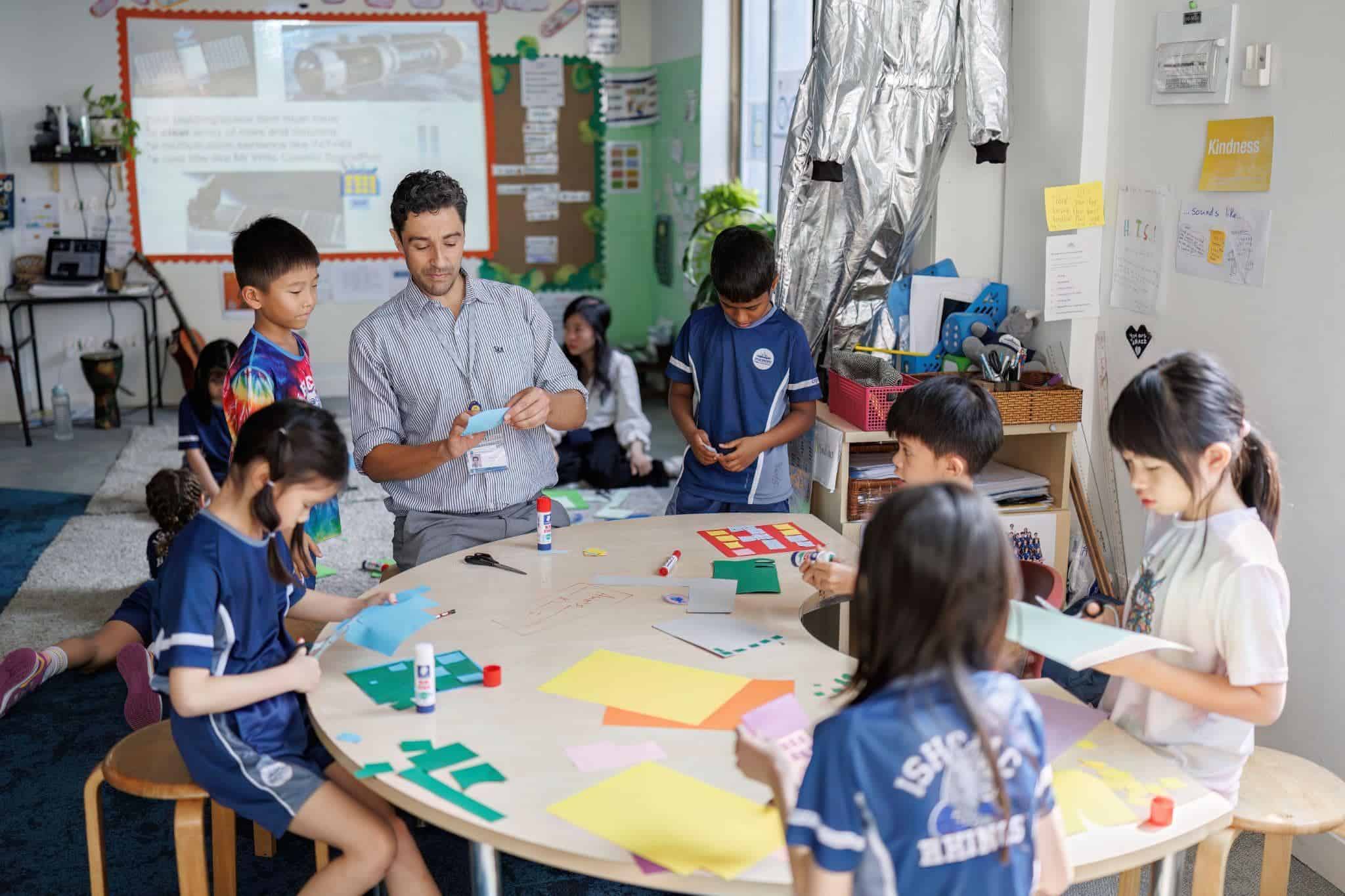 An engaging classroom scene at a prominent international school with students collaborating on creative projects and a teacher overseeing activities.