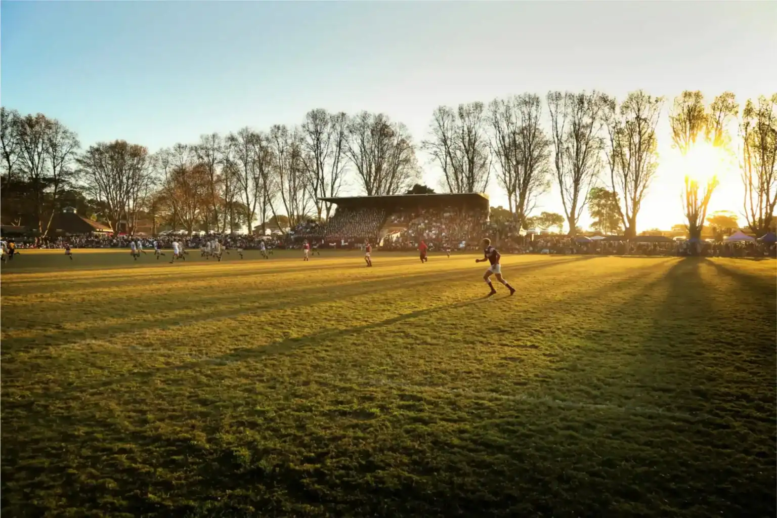 Youth rugby game playing outdoor during sunset at a school sports field.
