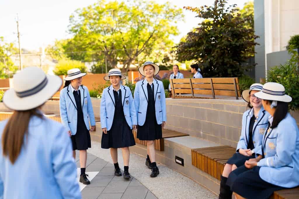 Students in uniform chatting outdoors at Walford Anglican School for Girls.