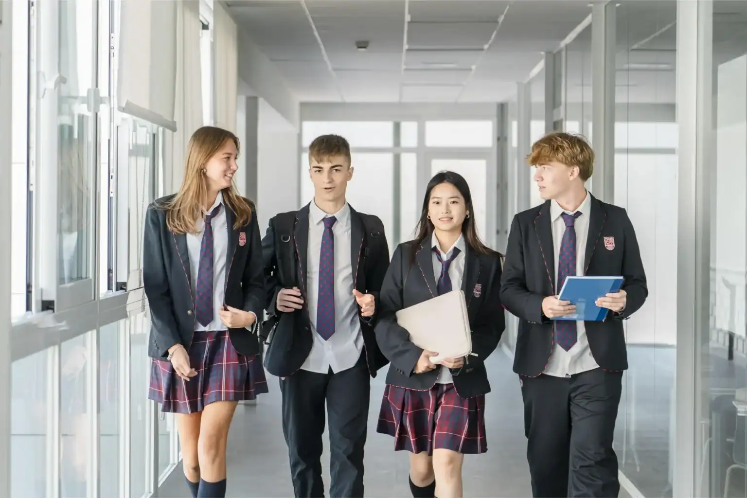 Students in school uniforms walking down a bright, modern hallway at a top international school.