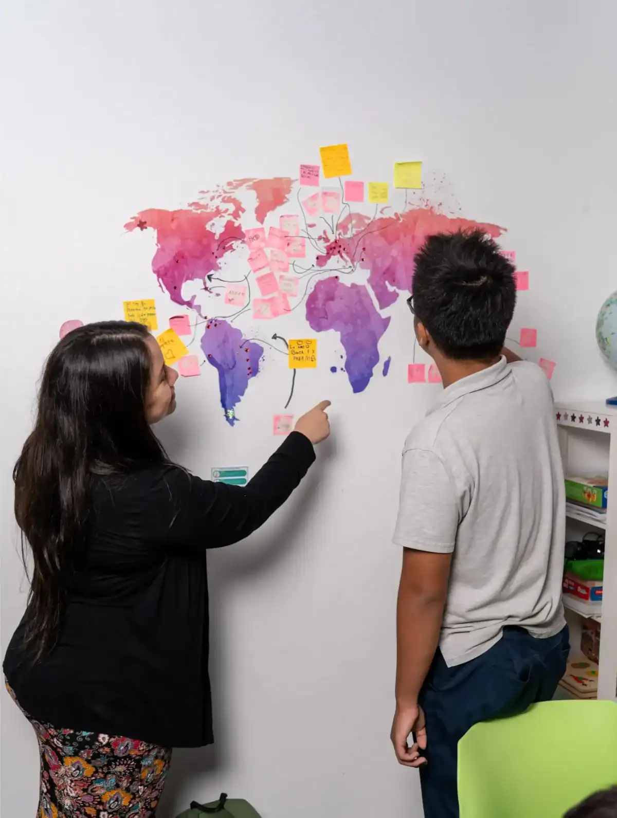 Diverse students collaborating on a world map with sticky notes.